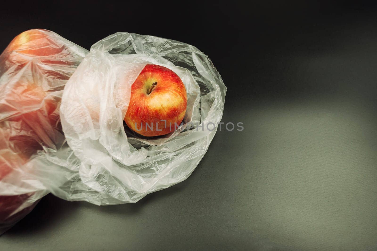 Fresh apples, encased in non-recyclable plastic, highlight the environmental challenges posed by excessive plastic usage, underscoring the need for sustainable alternatives.
