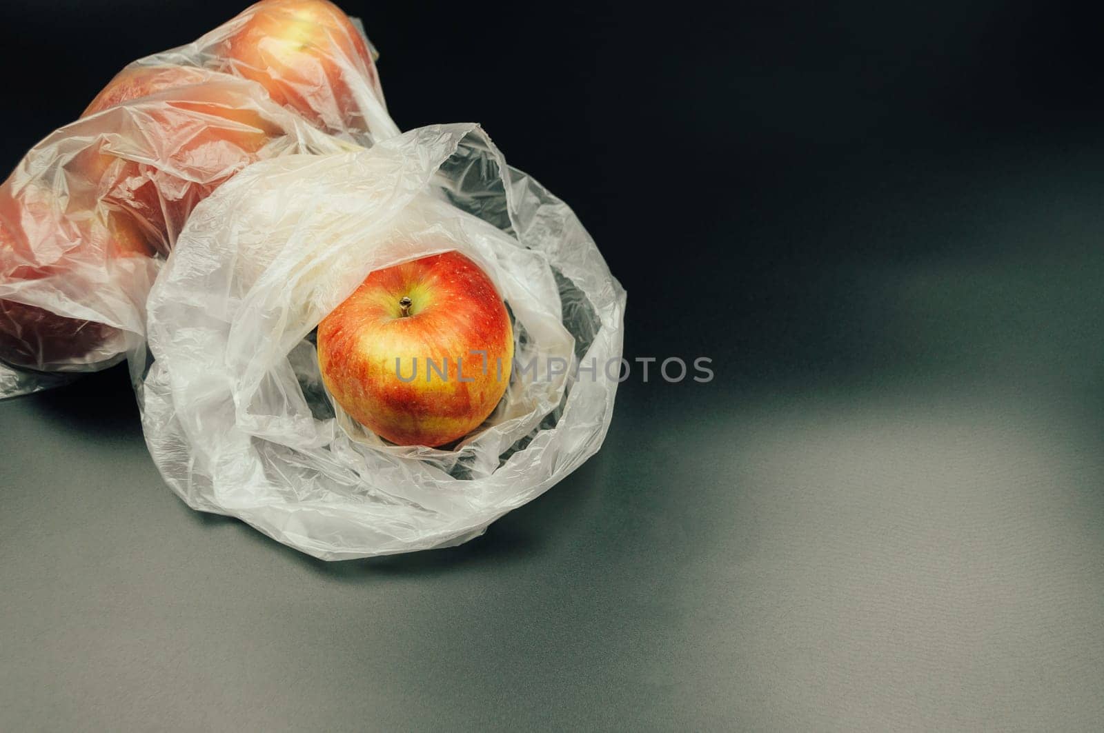 Fresh apples, encased in non-recyclable plastic, highlight the environmental challenges posed by excessive plastic usage, underscoring the need for sustainable alternatives.