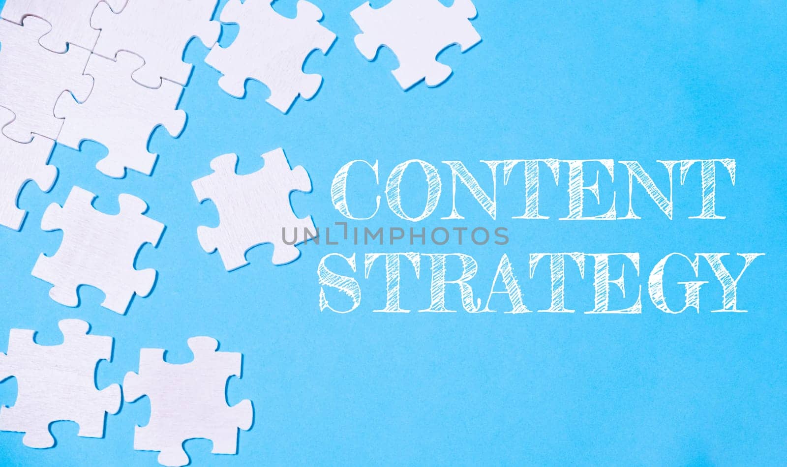 A jigsaw puzzle with the word content strategy written on it. The puzzle pieces are scattered across the image, creating a sense of disarray and complexity