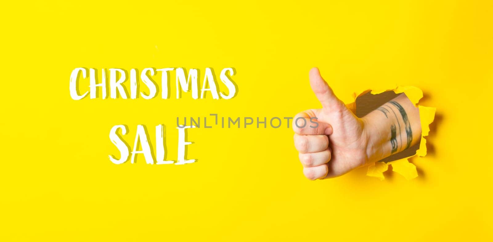 A hand giving a thumbs up with the words Christmas Sale written below it. The image has a positive and festive mood, as it is a thumbs up gesture