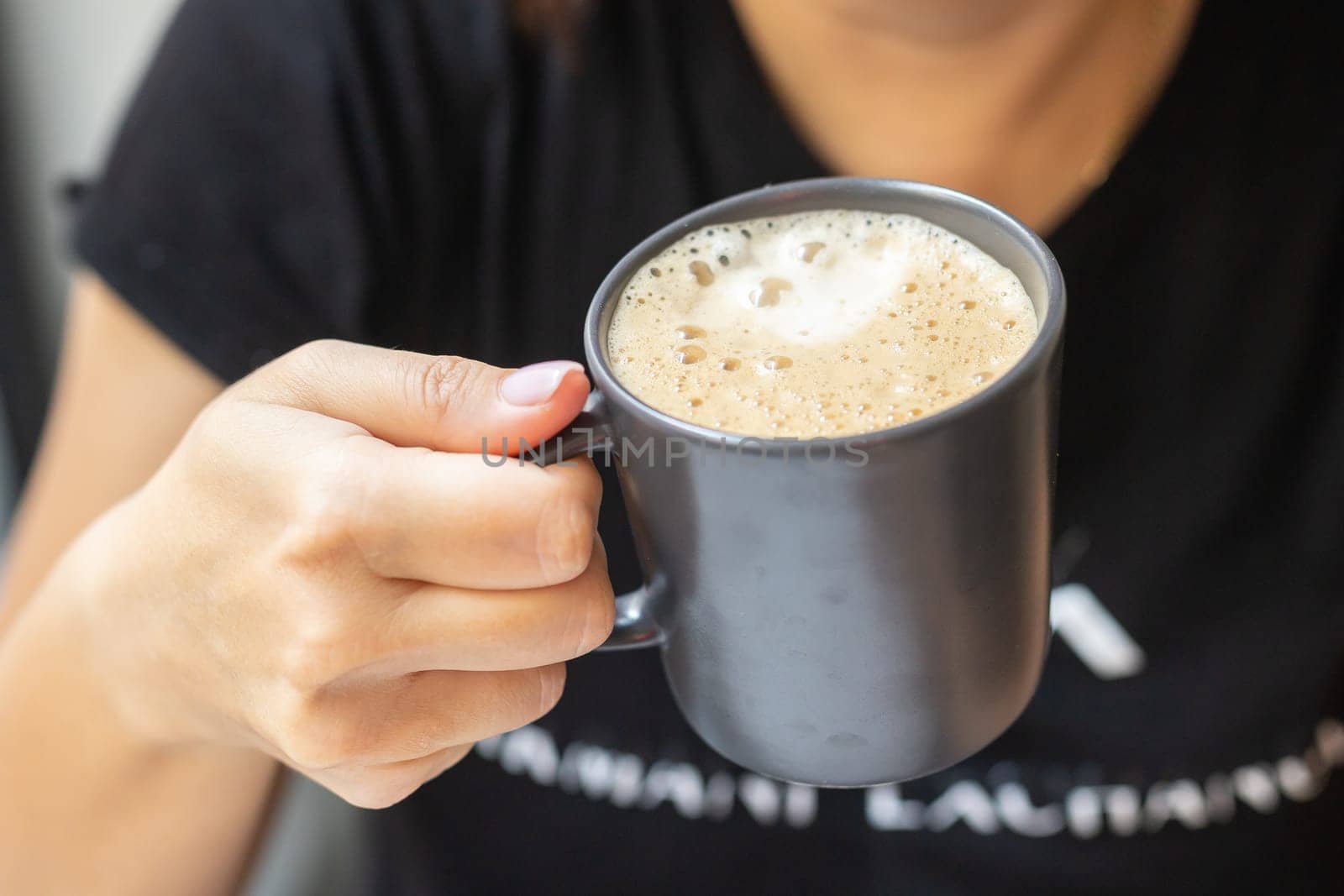 Young woman's hands holding coffee cup close-up. Top view of young female hands and a cup of coffee. by Satura86