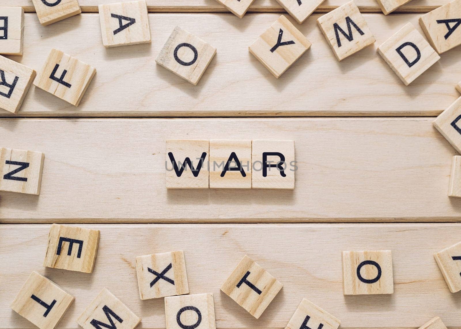 A wooden board with a bunch of wooden letters scattered around it. The letters spell out the word war