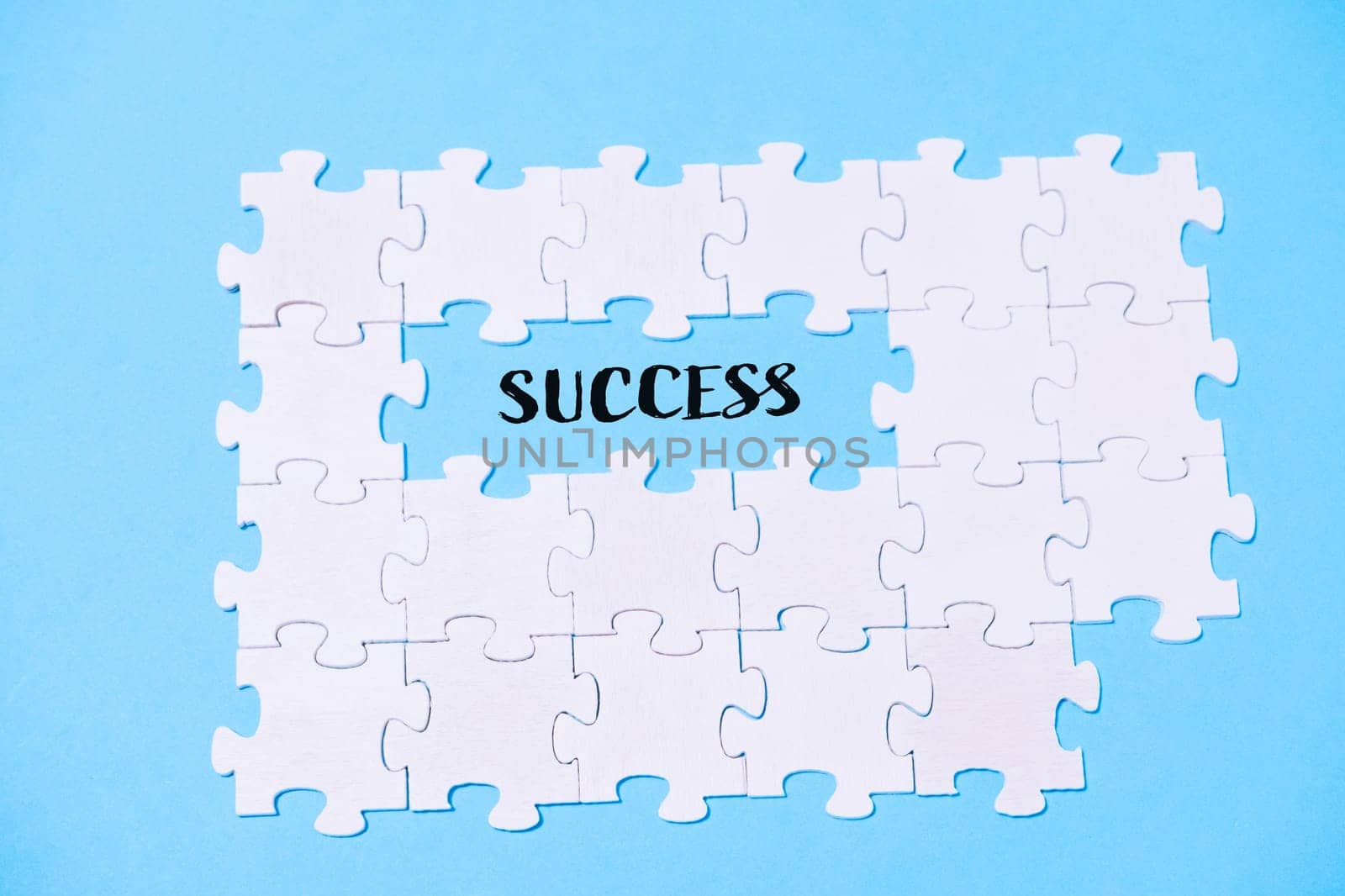 A puzzle with the word success written in the middle. The puzzle pieces are scattered around the word, creating a sense of accomplishment and achievement