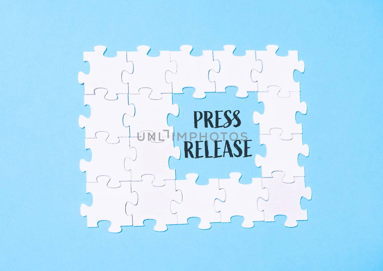 A puzzle with the word press release written in the middle. The puzzle is made up of white pieces and is on a blue background