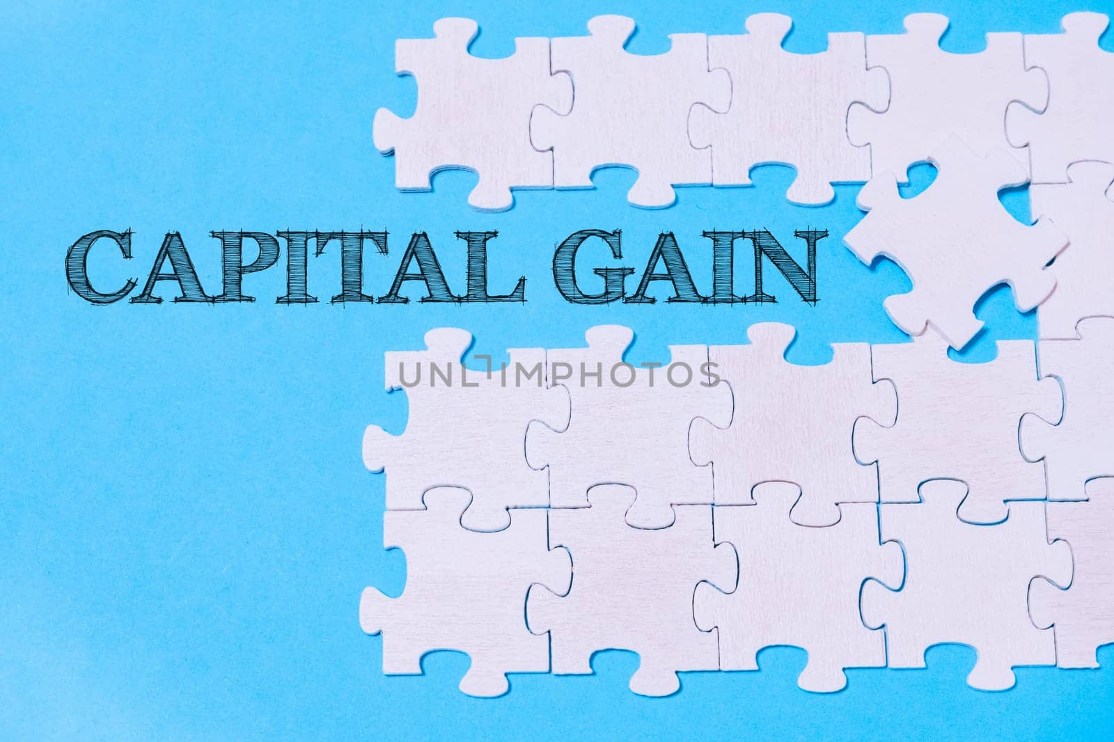 A jigsaw puzzle with the word Capital Gain written on it. The puzzle pieces are scattered across the image, creating a sense of disarray and uncertainty. The blue background adds a sense of calmness