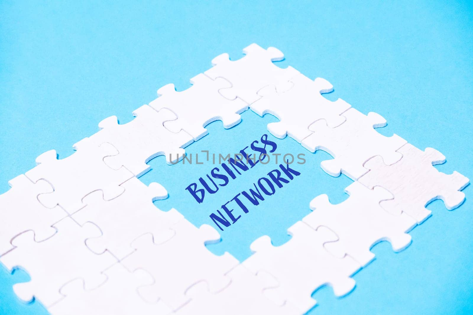 A white puzzle piece with the word business network written in blue by Alla_Morozova93