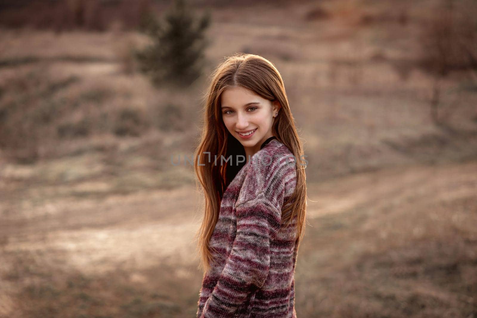 Attractive girl with sun in fluttering hair on nature background