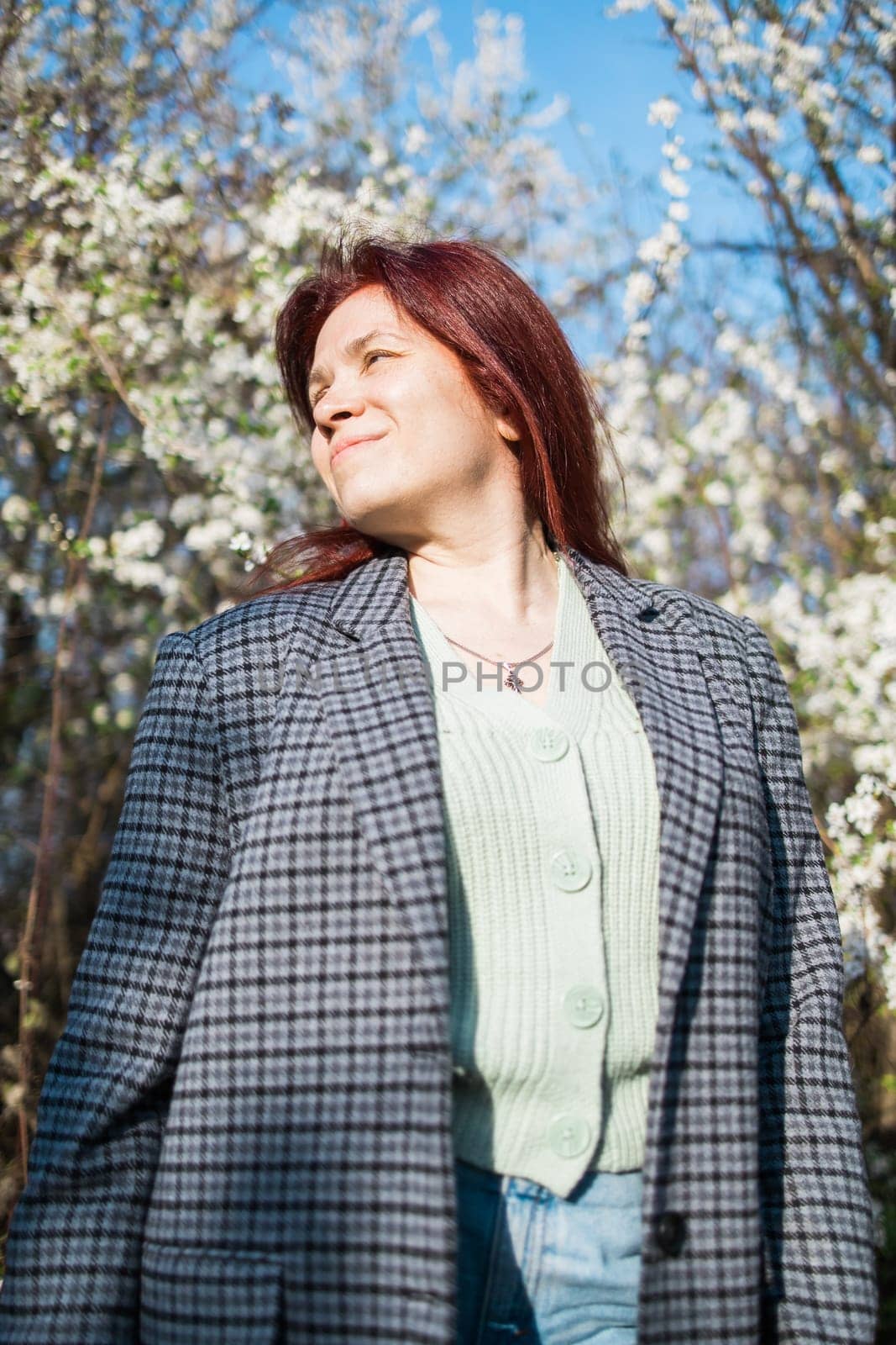 Beautiful young red hair woman near blooming spring trees alley. Youth and love, fashion and romantic and lifestyle concept. by Satura86
