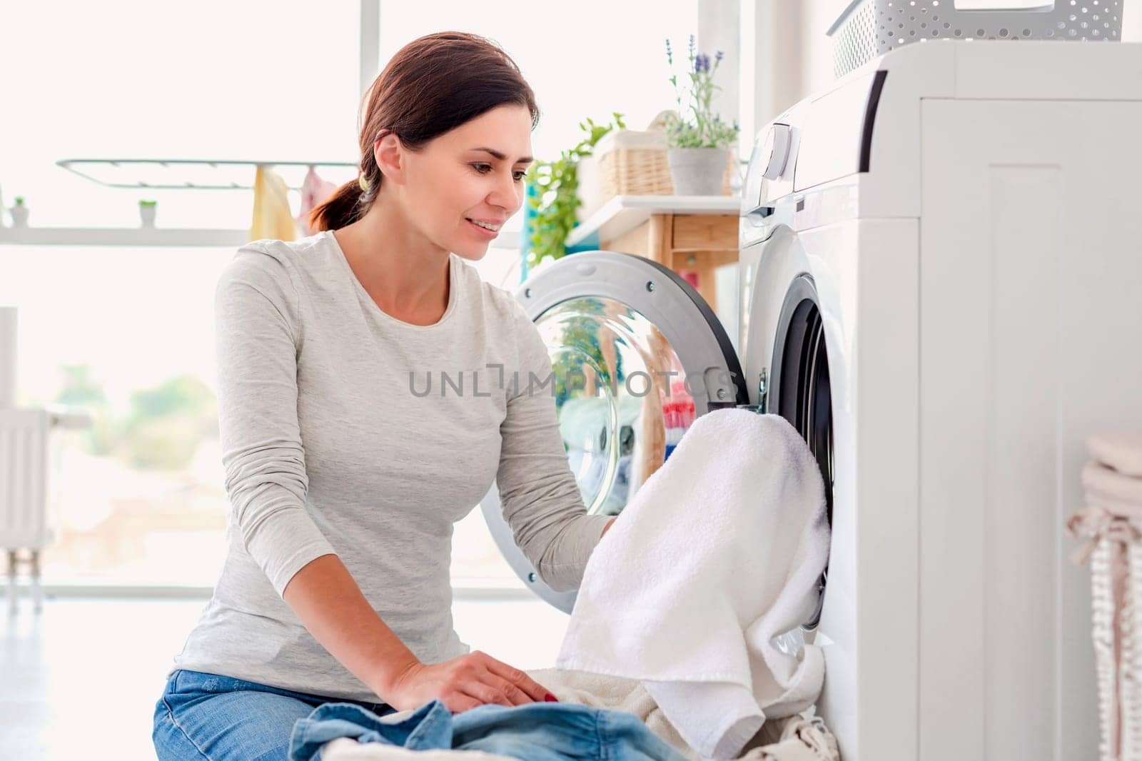 Woman putting clothes into washing machine by tan4ikk1