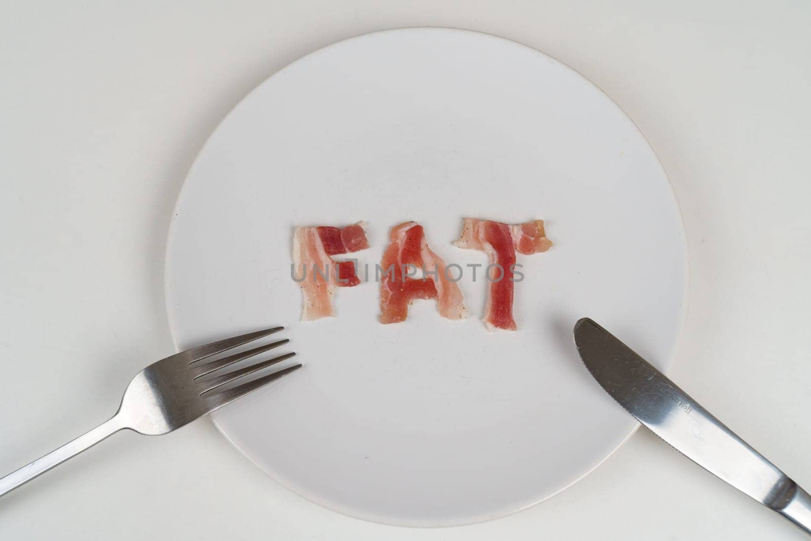 A plate with the word fat on it, accompanied by a fork and knife, symbolizing unhealthy eating habits.