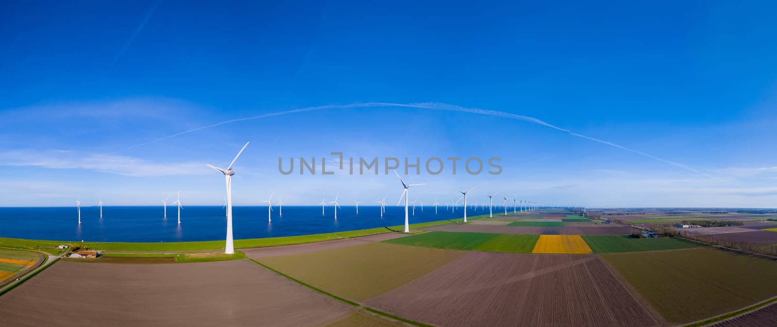 A mesmerizing aerial view capturing a wind farm near the ocean in the Netherlands Flevoland during the vibrant season of Spring.