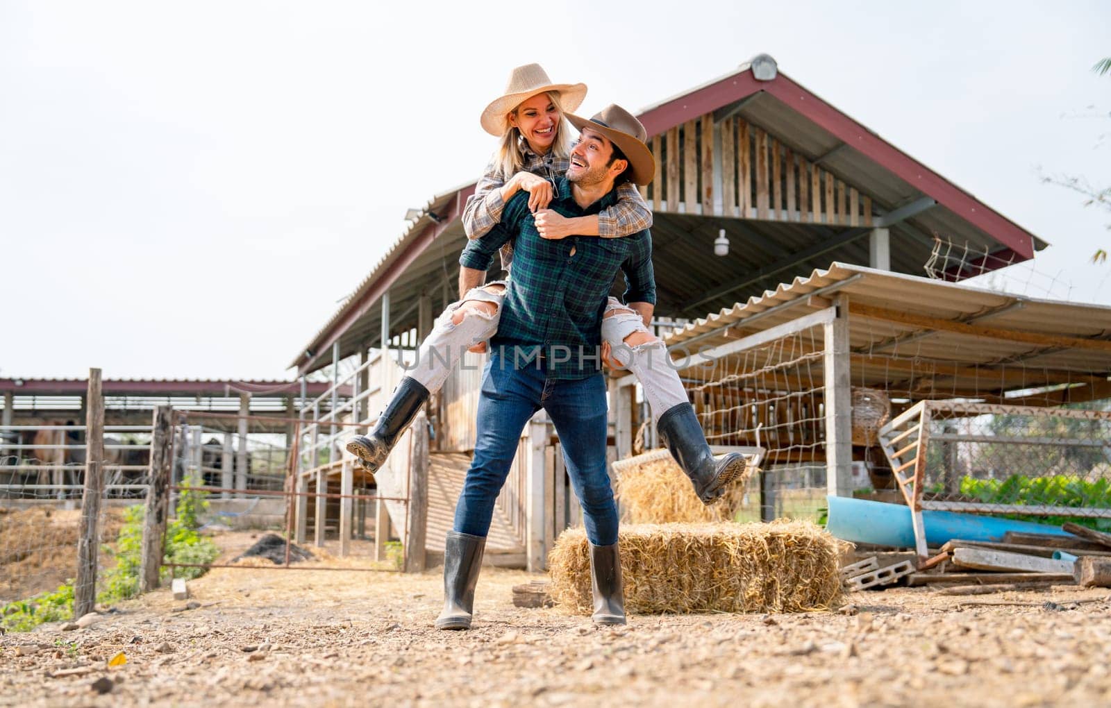 Caucasian man and woman farmer enjoy with woman riding on the back of man and go around the area of their farm with happiness and day light.