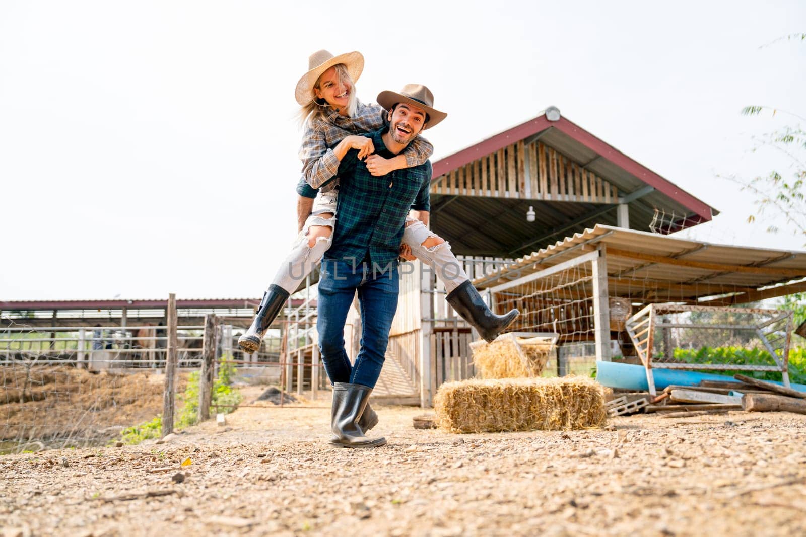 Caucasian man and woman farmer enjoy with woman riding on the back of man and run or walk around the area of their farm with happiness and day light.