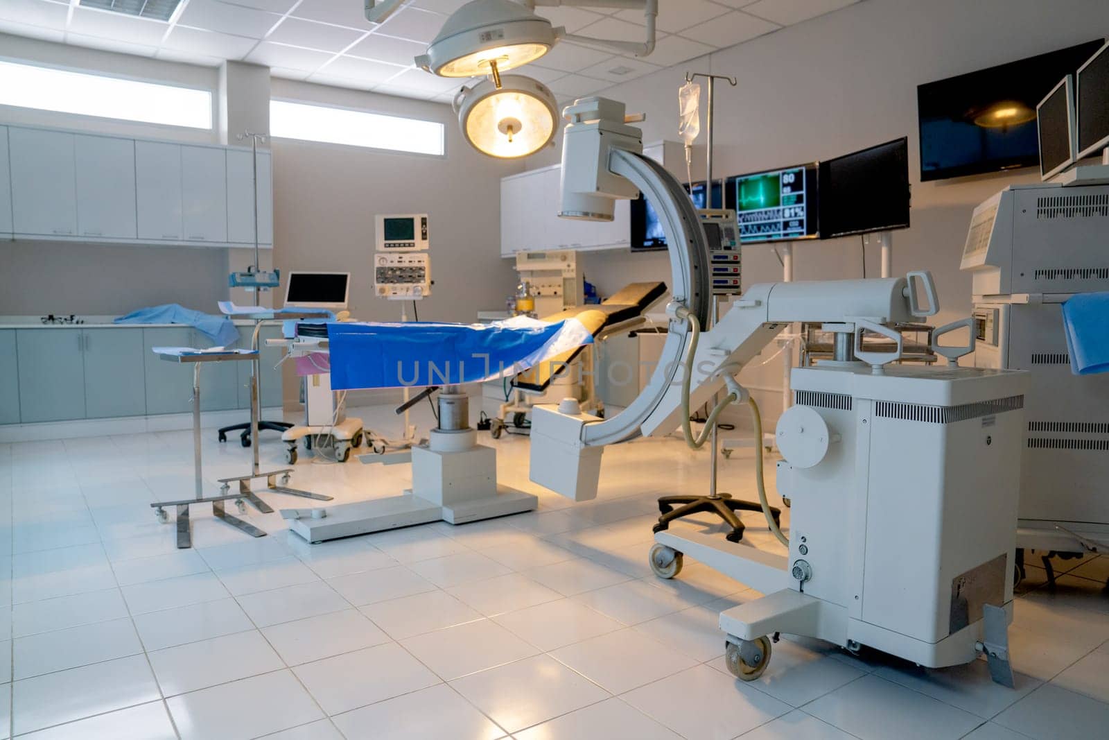 Wide shot of empty operation room with no people and view through clear mirror contain tools and instrument to support for treatment the patient.