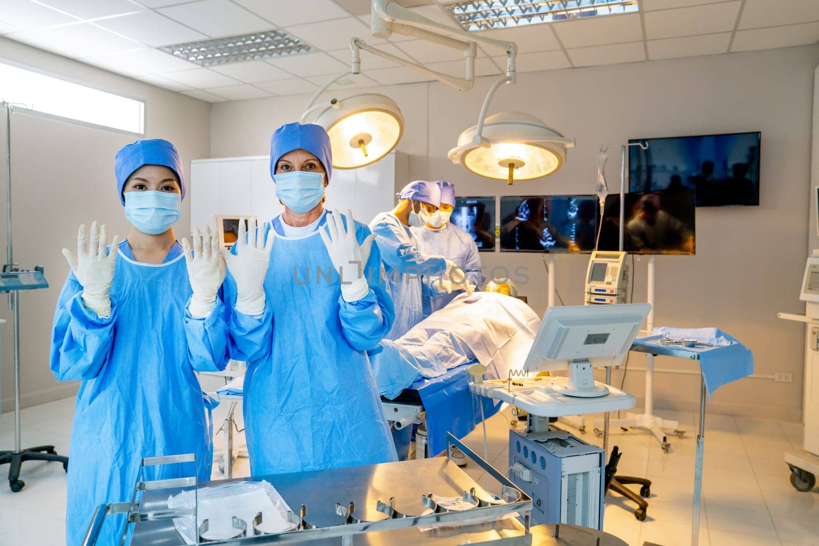 Portrait of nurse and doctor with blue gown clothes show both hands and stand in front of their team in operation room.