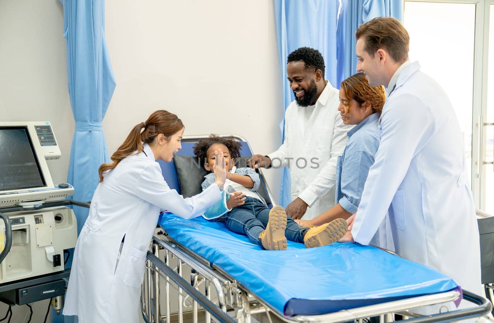 Asian doctor woman take care child patient and other doctor also family stay beside the bed in area of emergency room.