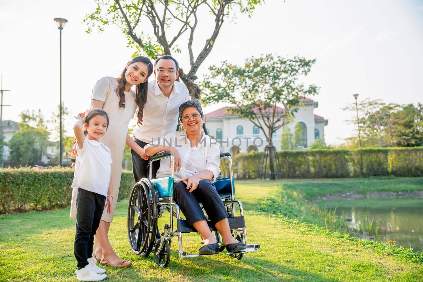 Asian family stay in garden in area of their home village with soft light in evening and they look at camera with smiling.