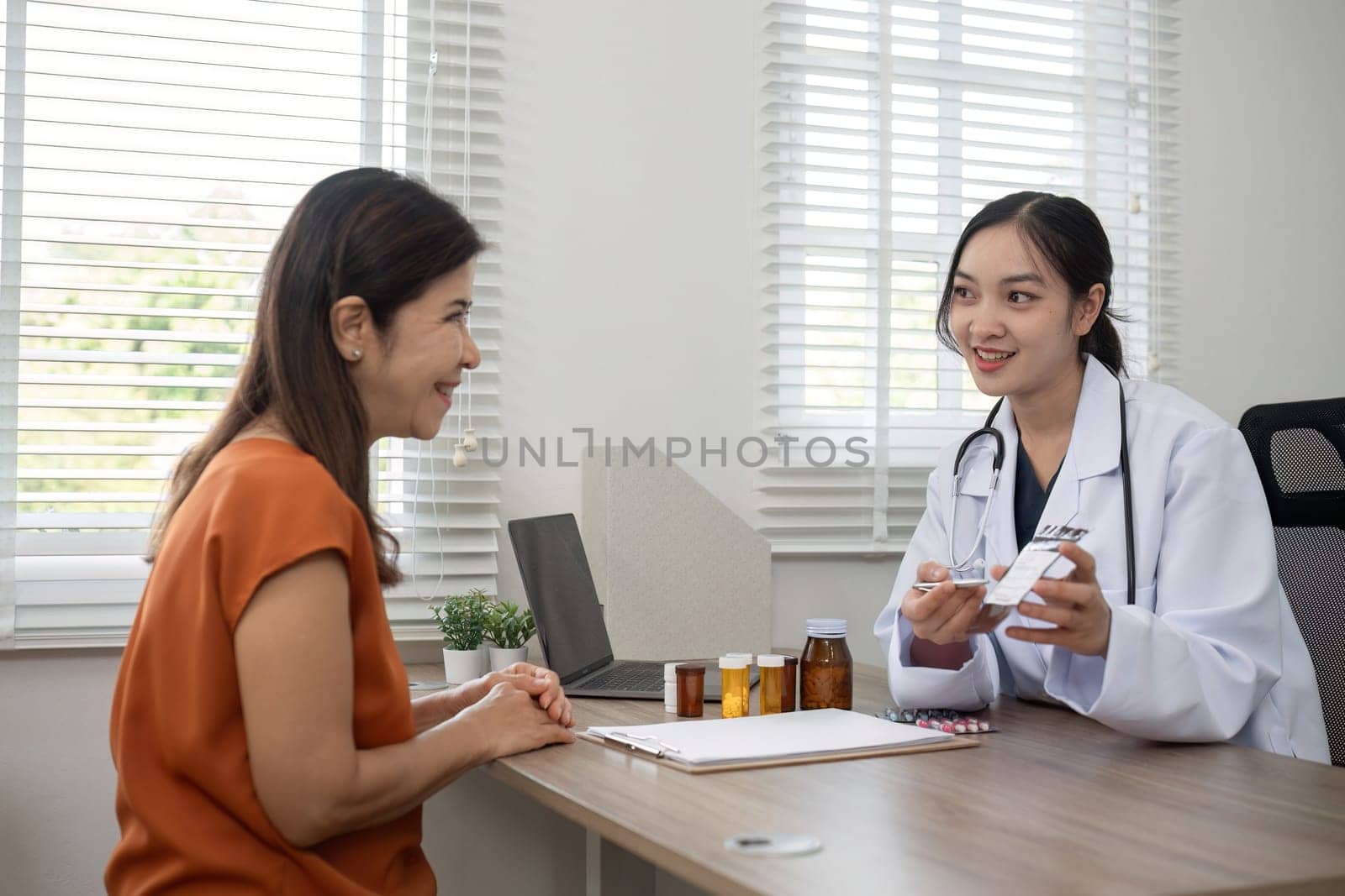 A female doctor and an elderly patient are giving advice on health care and the use of medicine to nourish the body. by wichayada