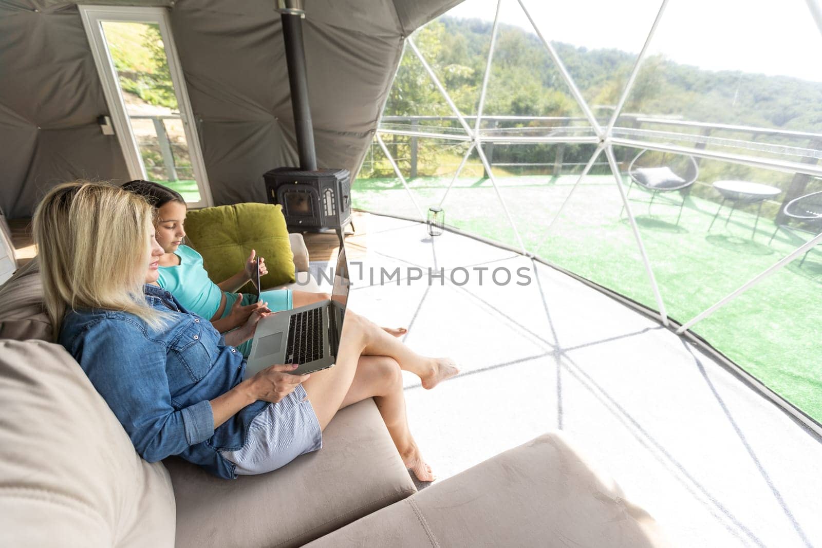 This is our mother and daughter time. Shot of a young mother and daughter using a laptop and digital tablet on the couch at home by Andelov13