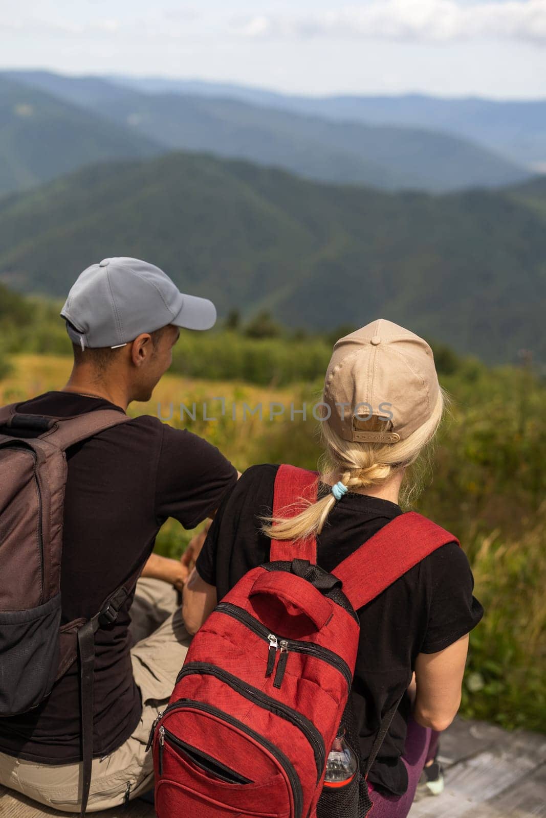 People sit on the ski elevator. View from the back. Summer, green forest. summer family vacation in the mountains