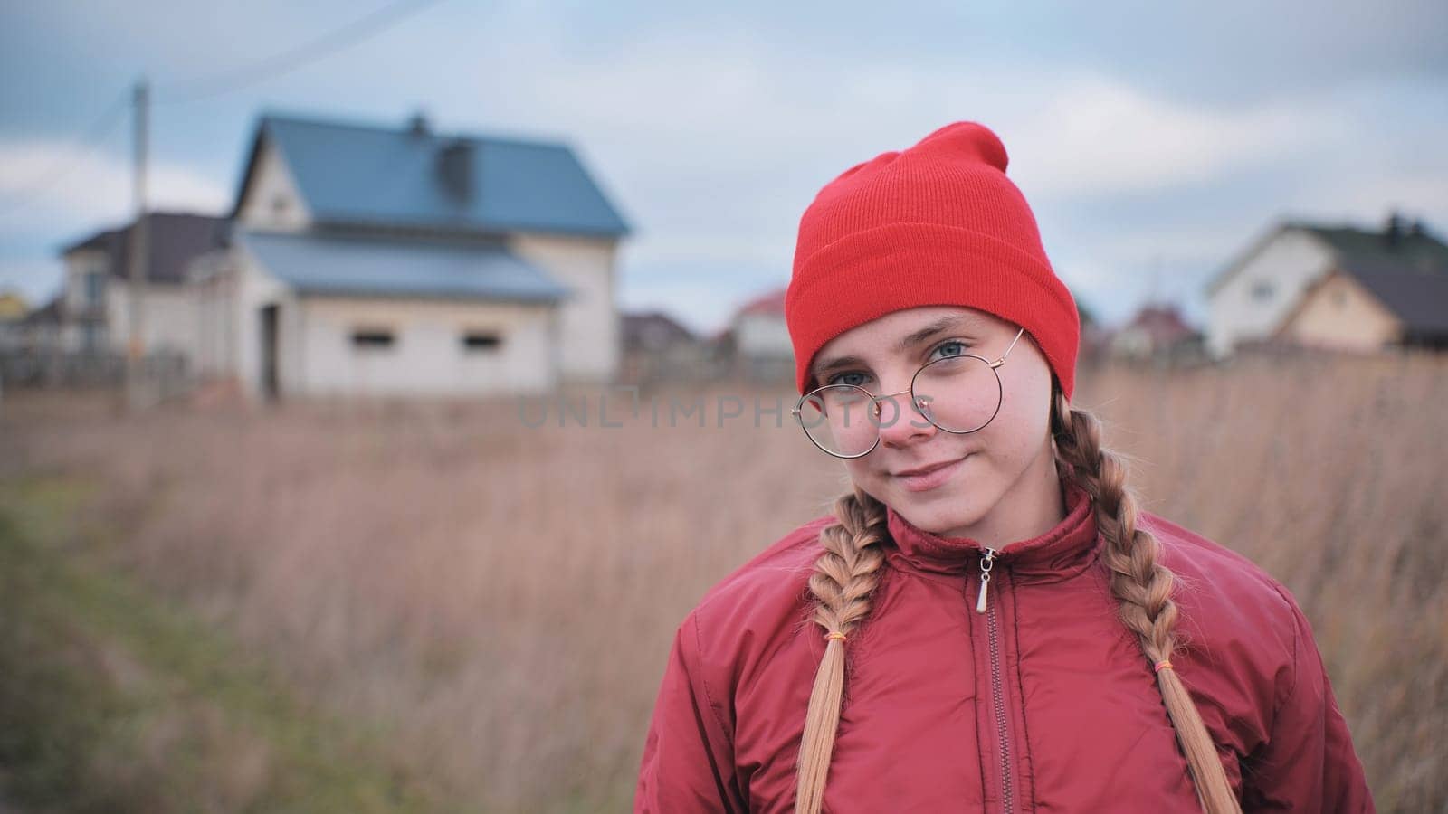 Portrait of a teenage girl in glasses wearing red clothes outside in the fall. by DovidPro