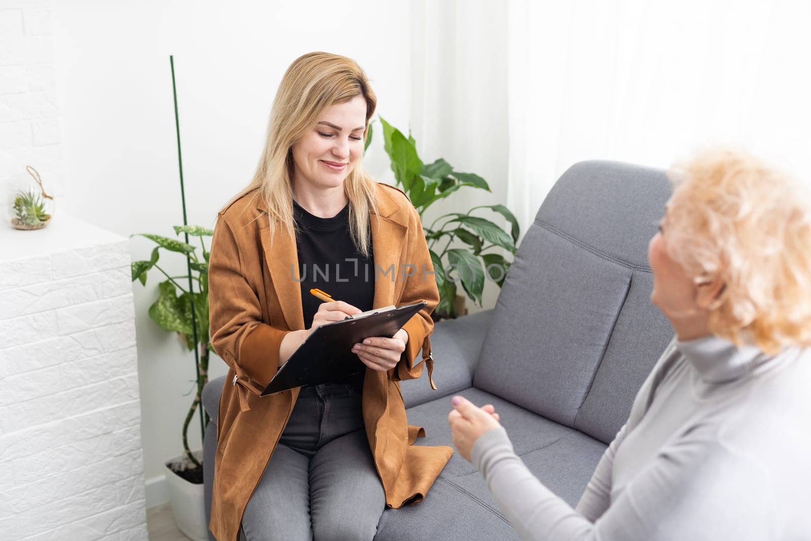 Depressed senior woman talking with female psychologist.