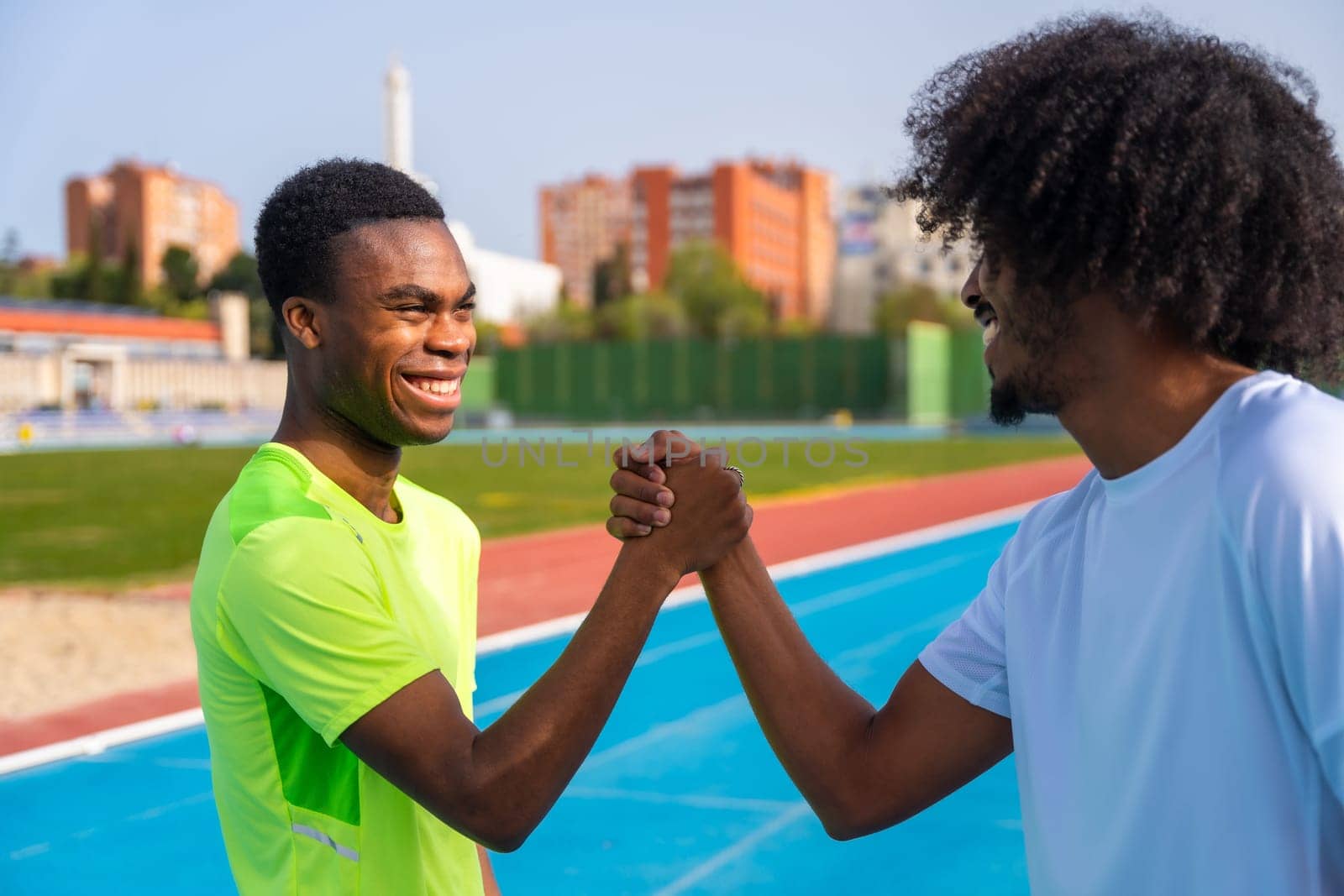 Runners shaking hands working out together in a running track by Huizi
