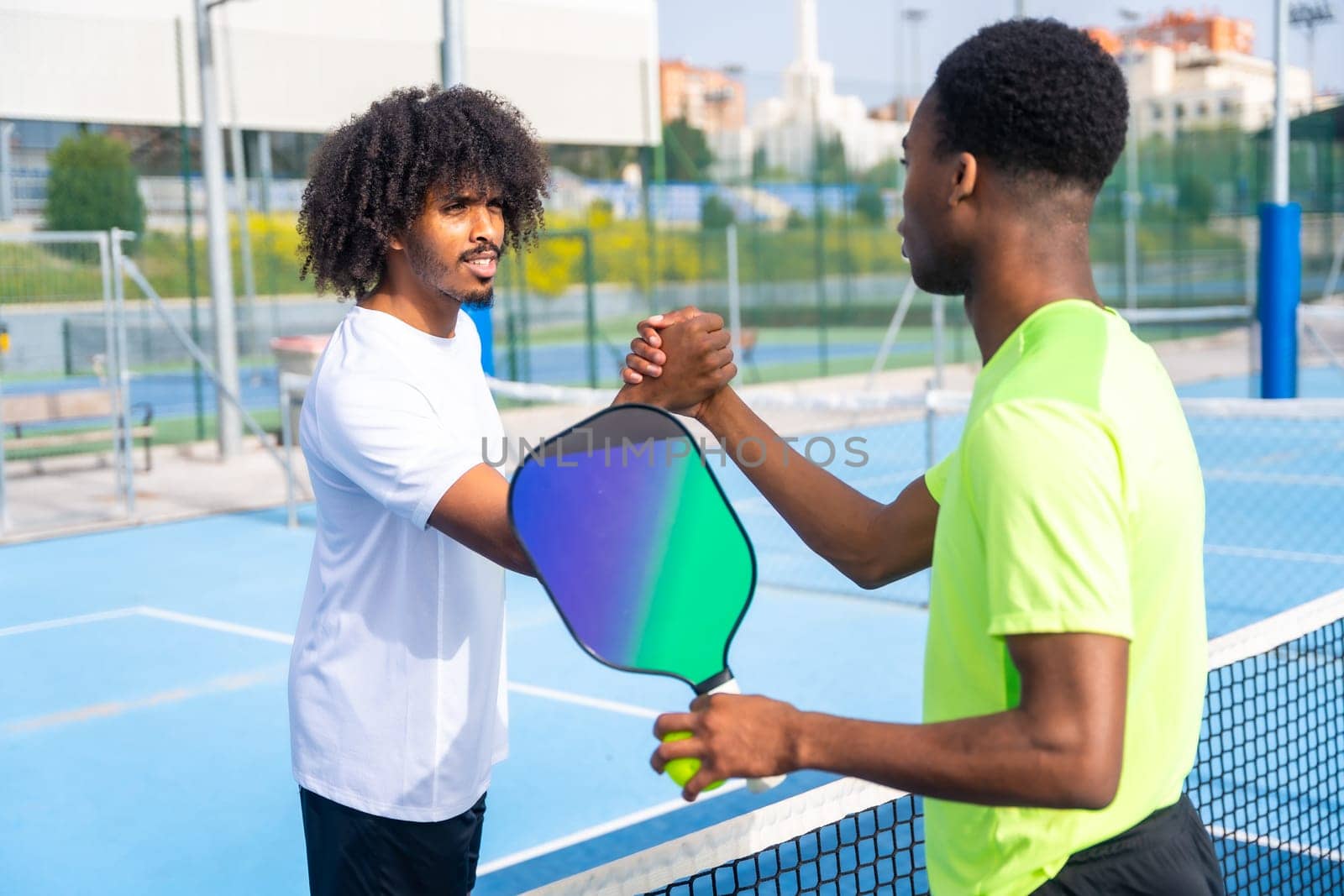 Men shaking hands before playing pickleball in an outdoor court by Huizi