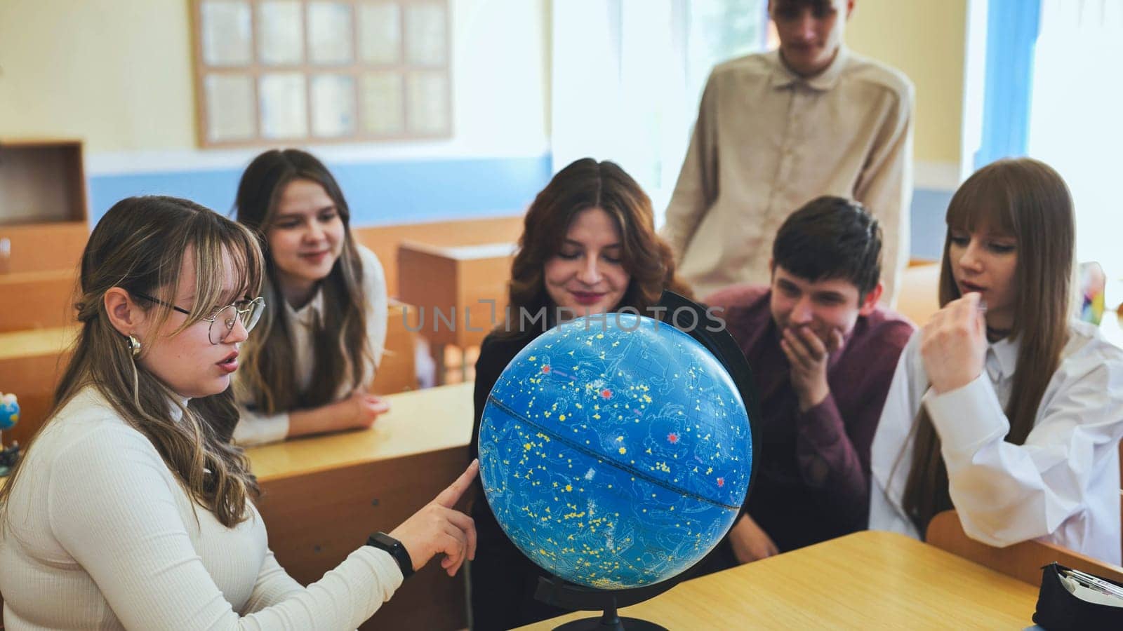 Students look at a globe of the starry sky in a classroom at school. by DovidPro