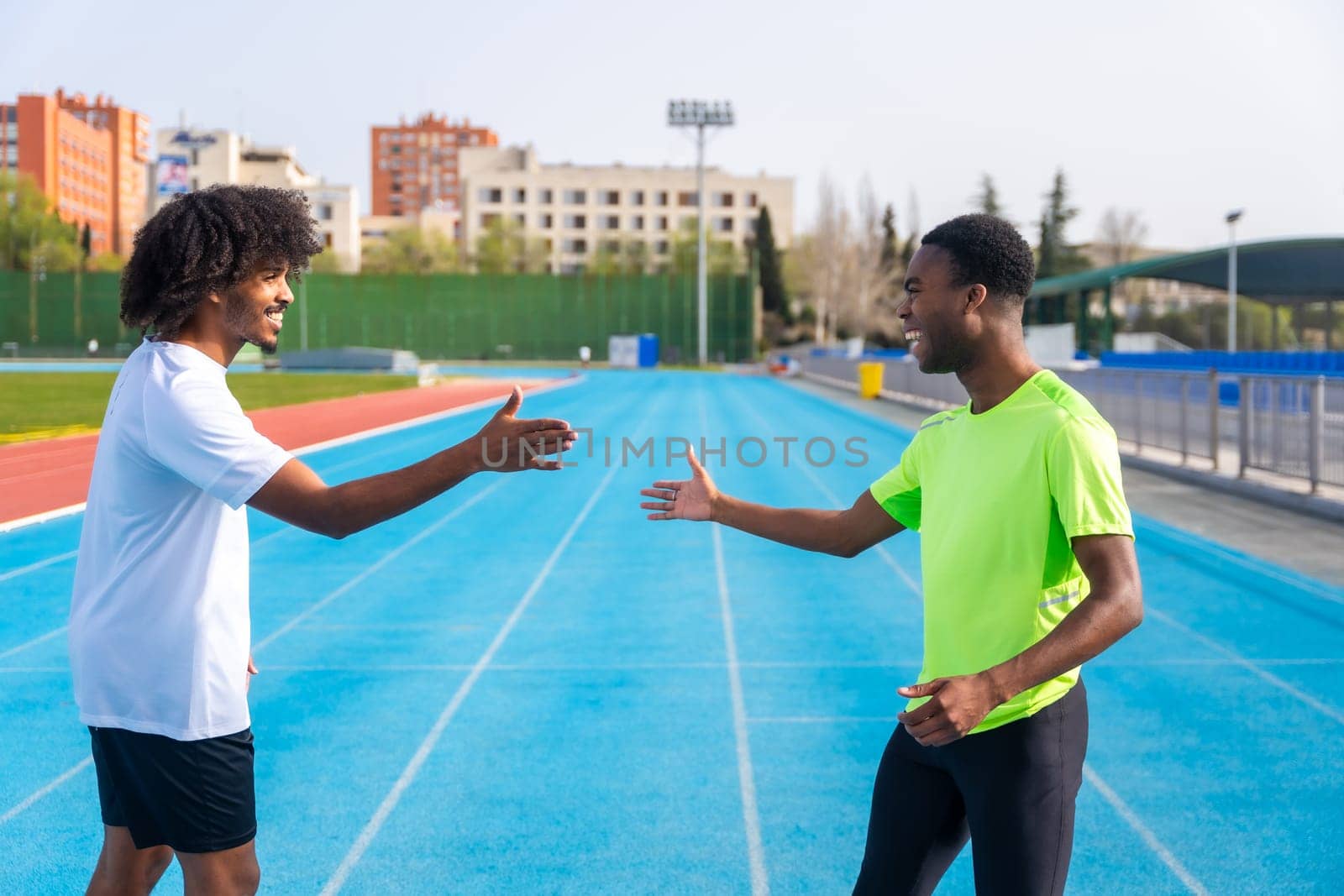 African american young happy runners high-fiving in a running track by Huizi