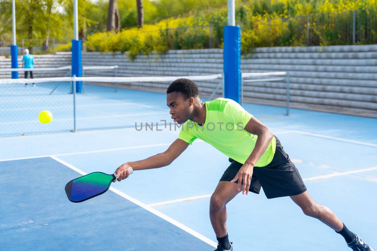 Concentrated man playing pickleball in an outdoor court by Huizi