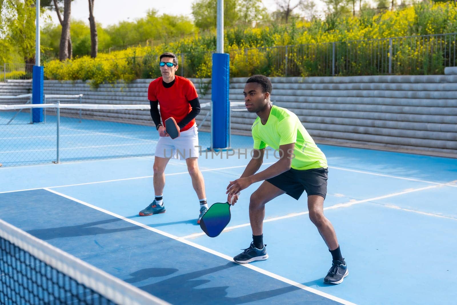 Multiracial team of pickleball players in an outdoor court by Huizi