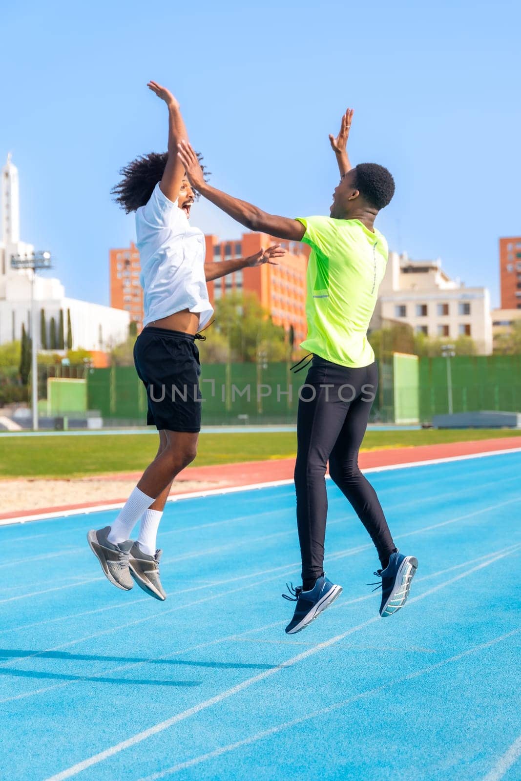 Excited running team jumping high-fiving in a running track by Huizi