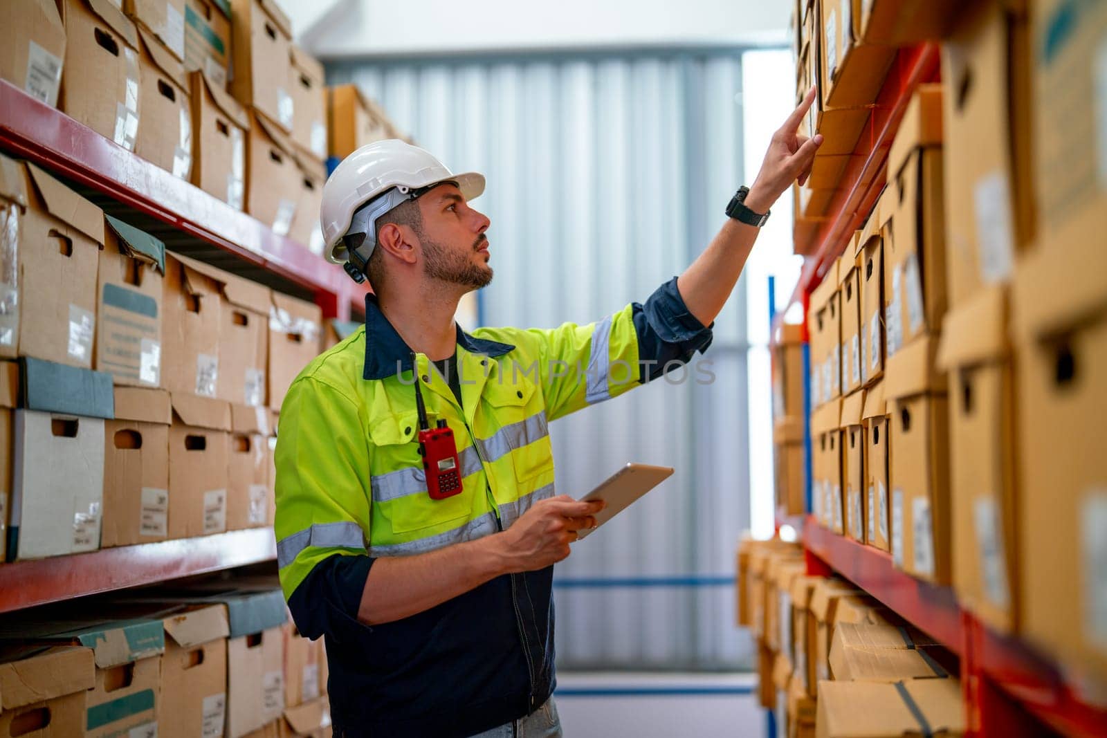 Professional warehouse worker hold tablet and point to check the product on shelves in workplace. The concept of good system support the worker for stock and shipment factory industry.