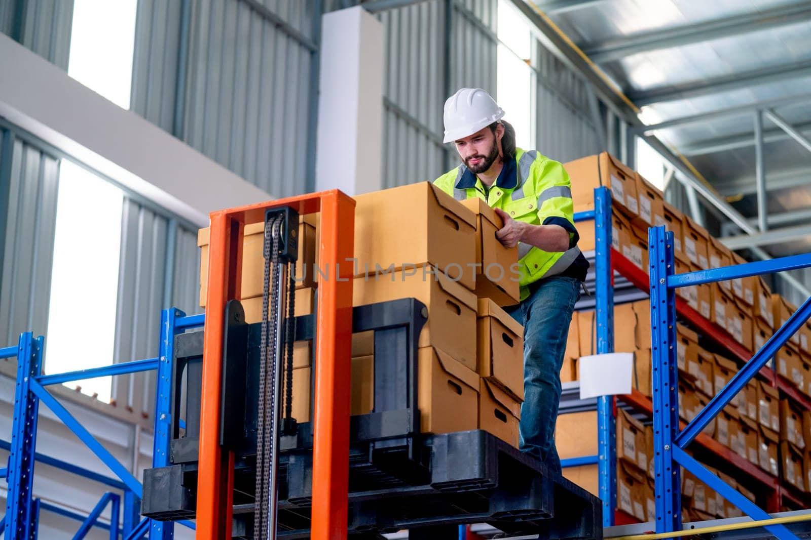 Professional warehouse worker man hold and carry box out from cargo truck that lift up the state for the man on upper level in workplace. by nrradmin