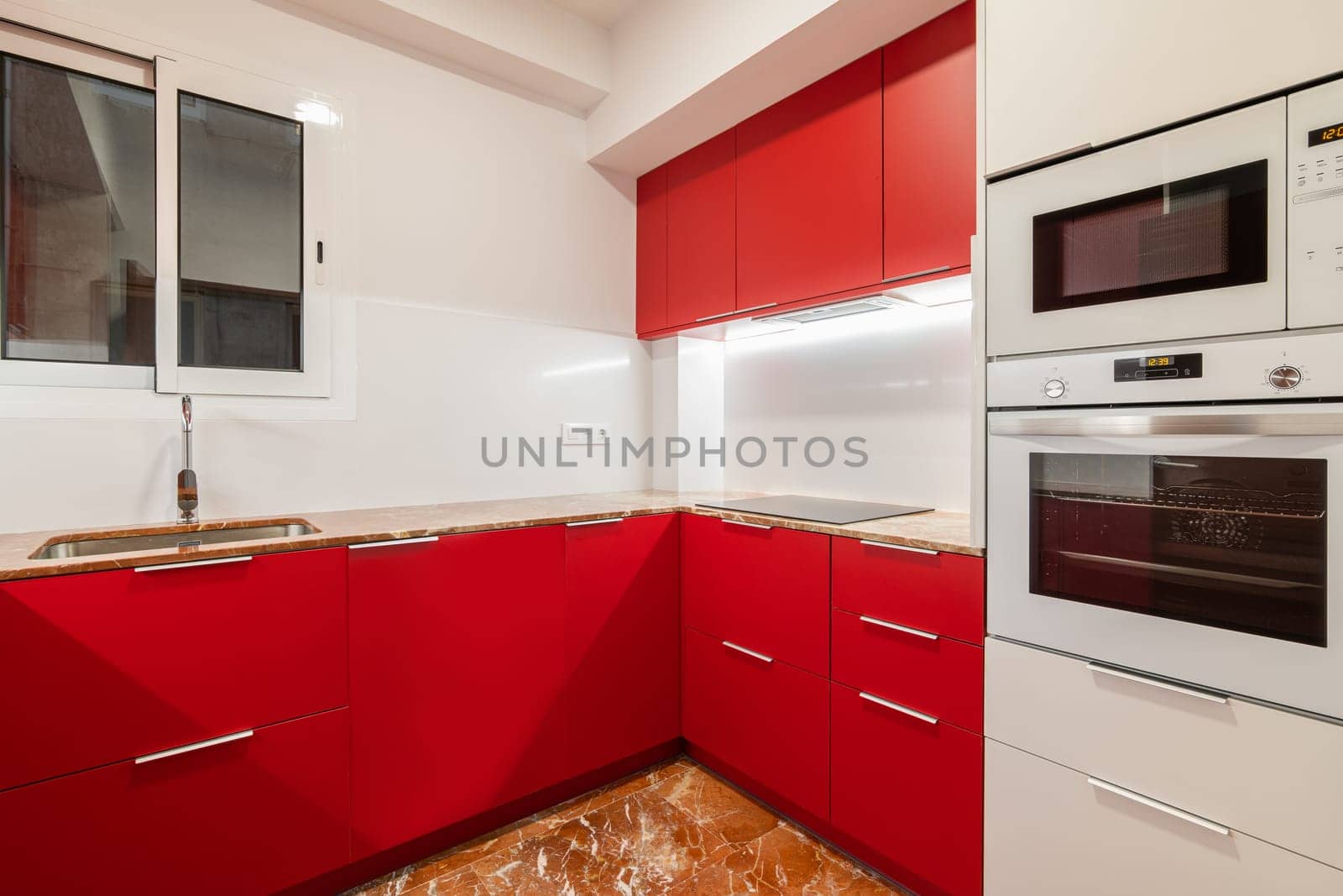 A modern kitchen with stylish red cabinetry and white appliances.