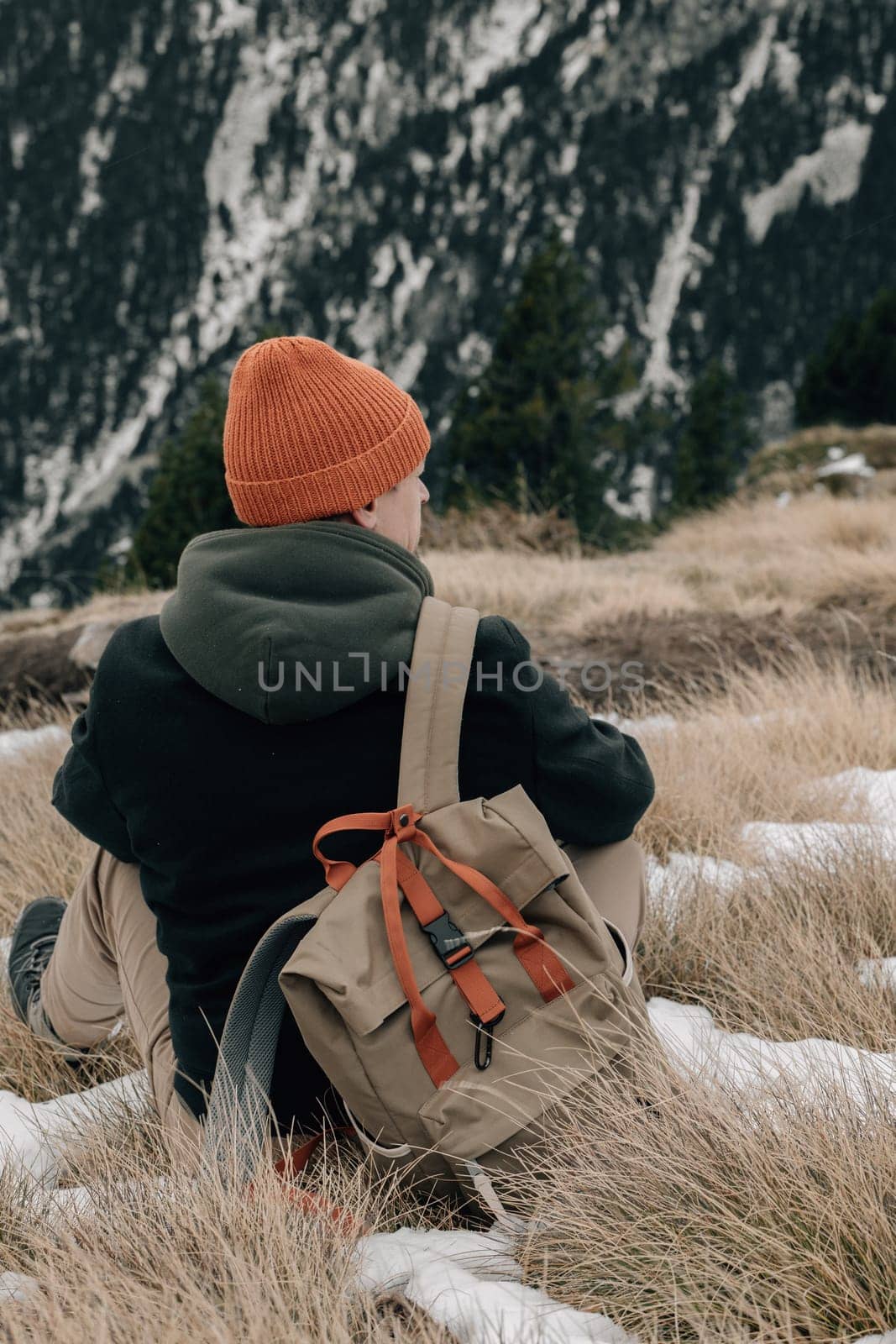 A solitary figure takes a moment to rest and admire the mountain view, surrounded by a snowy landscape.