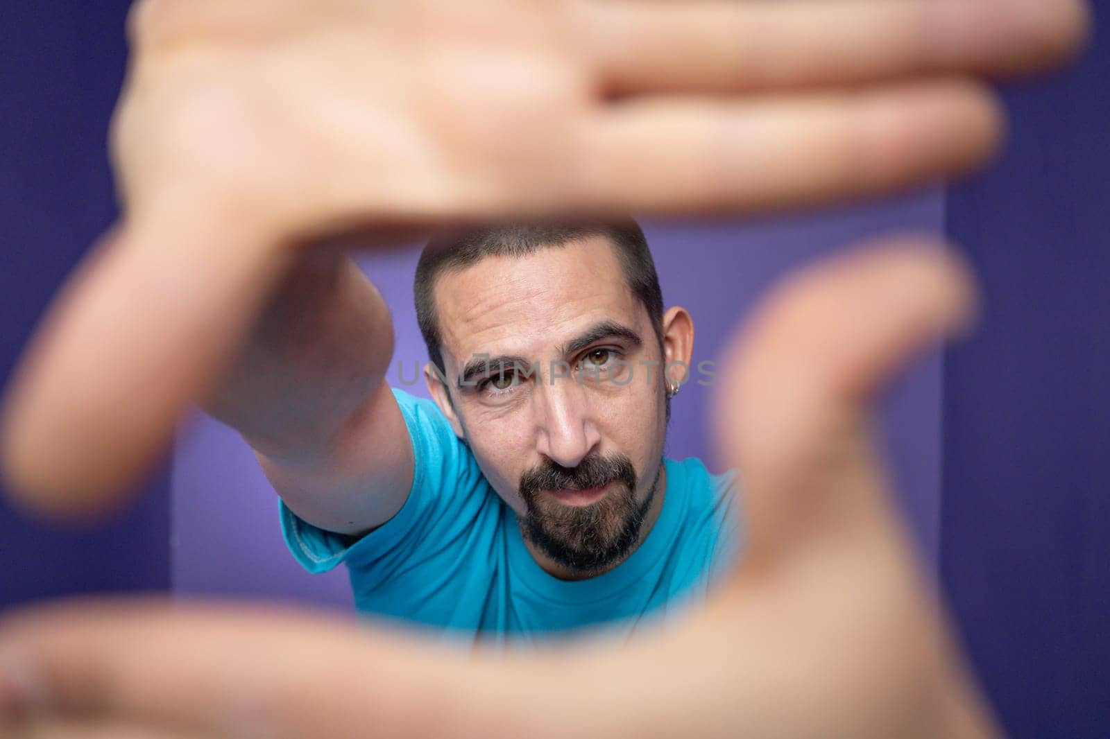 Young man doing frame using hands and fingers, isolated over purple background by PaulCarr