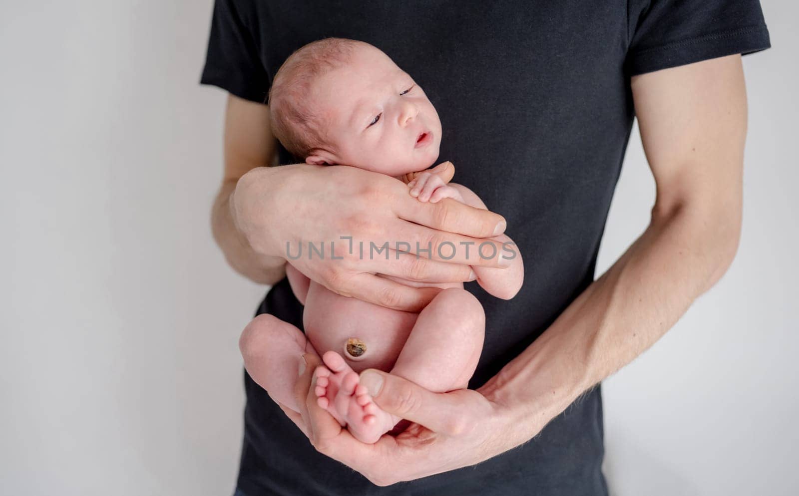 Newborn Baby Sleeps In Daddy'S Arms During Infant Photo Session