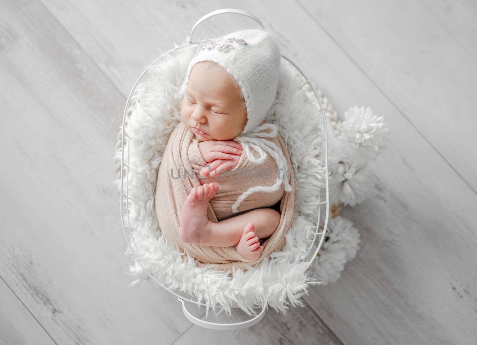 Newborn Girl Wrapped In A Blanket And Hat, Sleeping In A Beige-Toned Basket, Is Captured In A Professional Newborn Photoshoot