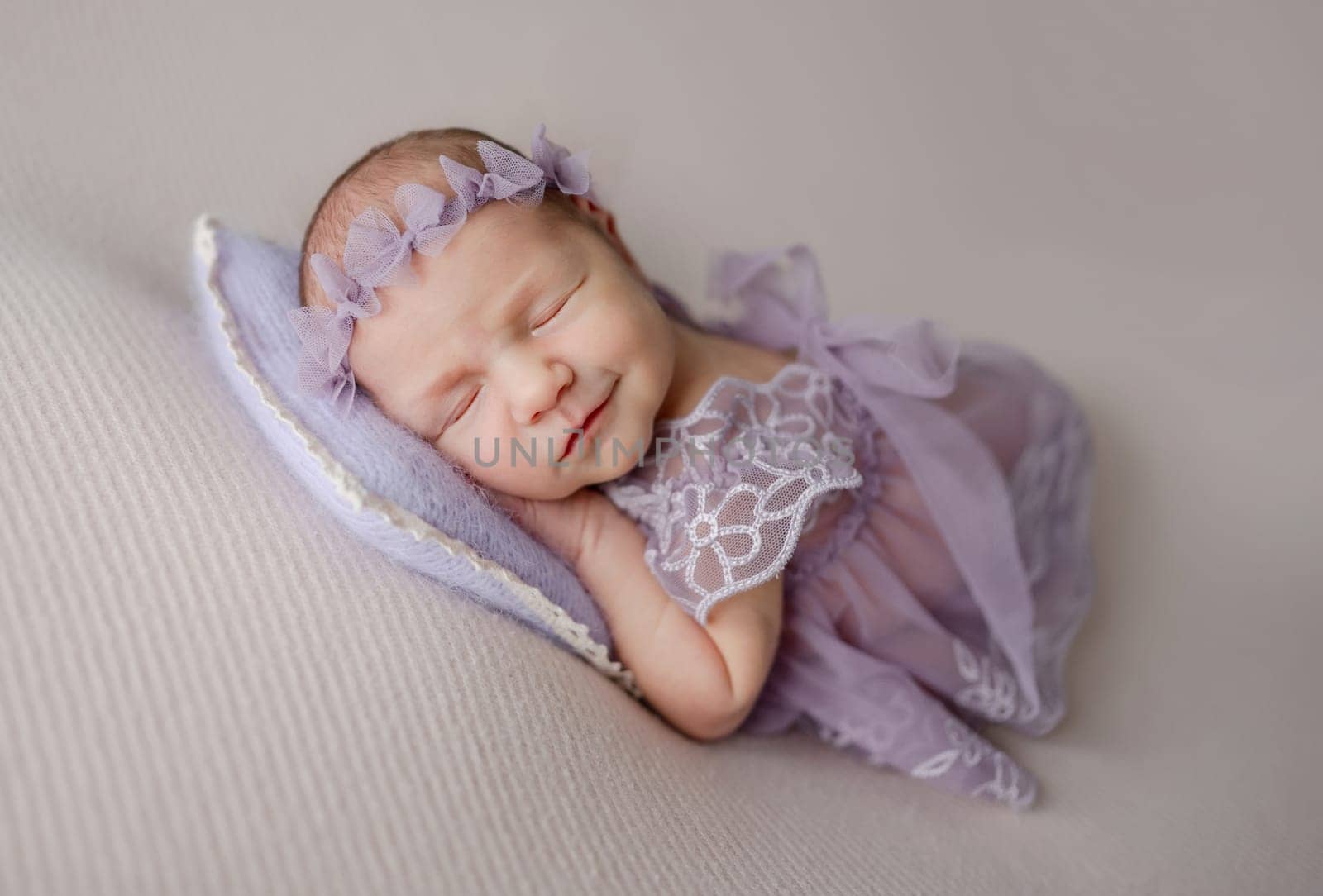 Newborn Girl In Lace Dress Sleeps And Smiles In Her Dream In Lilac Tones Photo