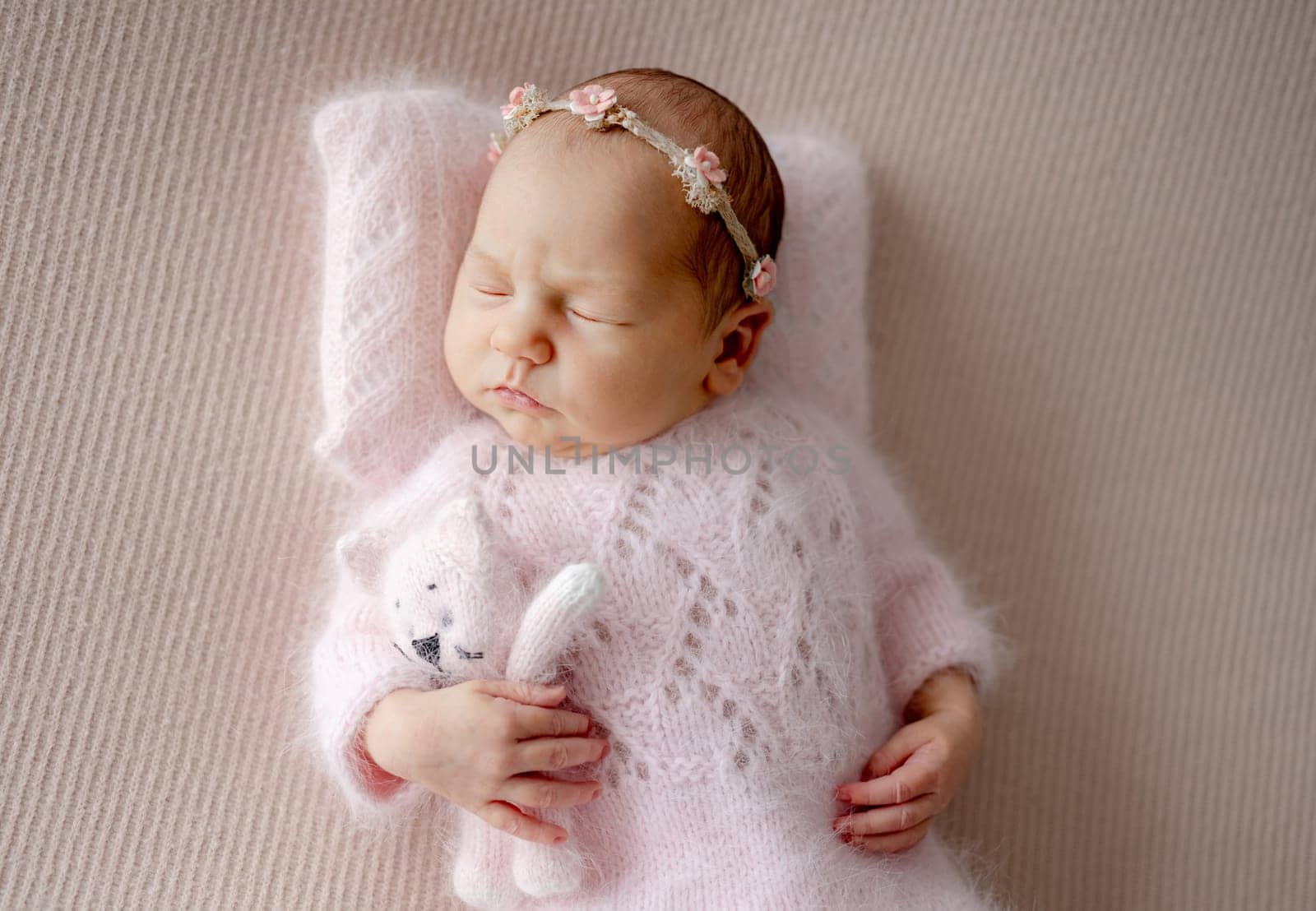 Newborn Girl In Pink Suit Sleeps With Toy Cat During Professional Newborn Photoshoot