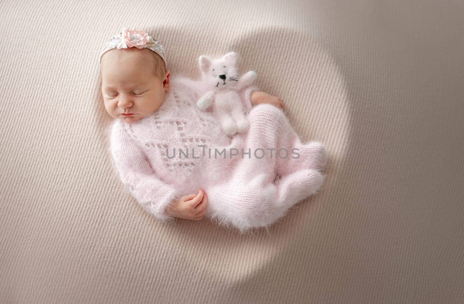 Newborn Girl In Pink Suit With Toy Cat Sleeps In Wooden Heart-Shaped Bowl During Professional Newborn Photoshoot