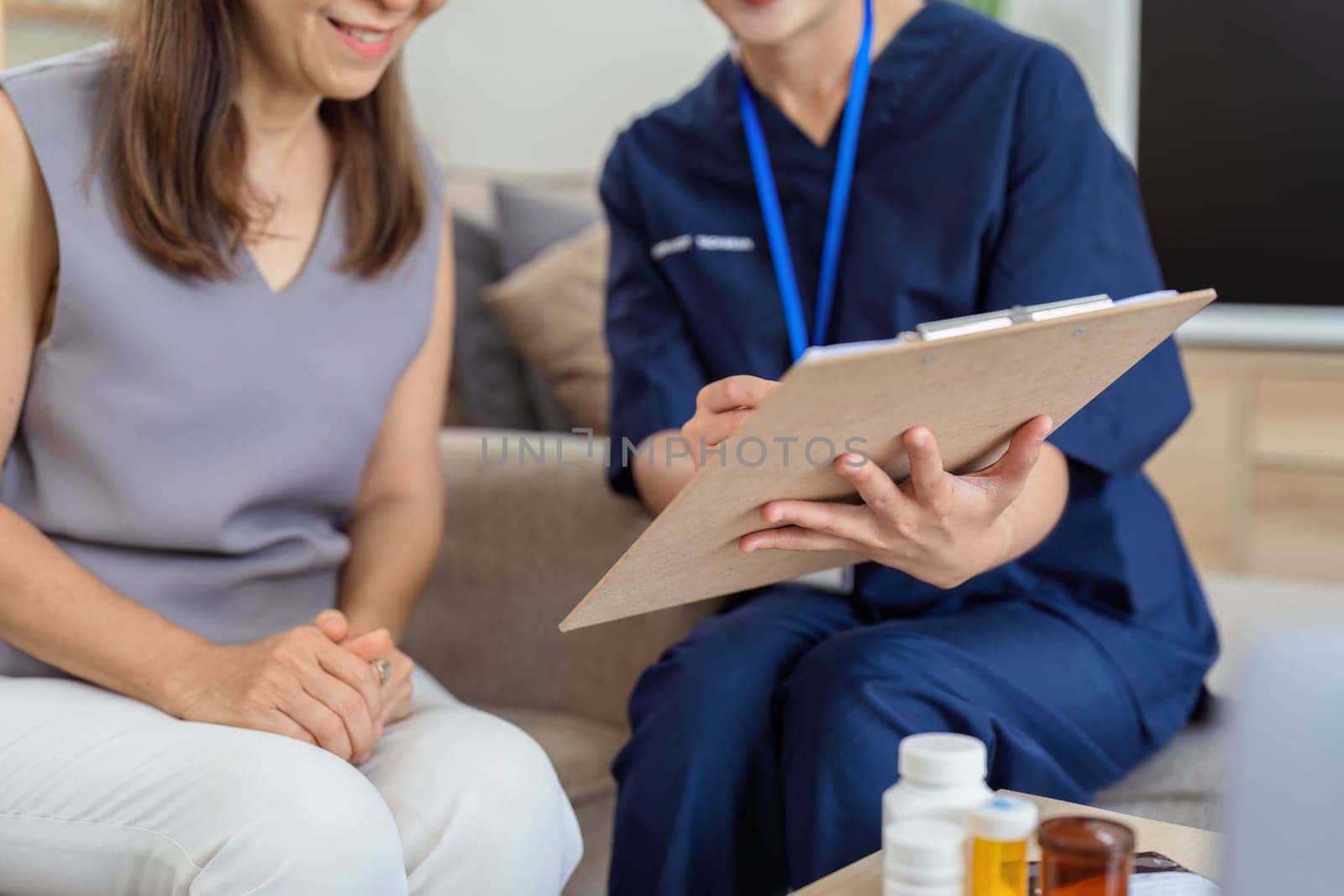 healthcare worker filling in a form with a senior woman during a home health visit.