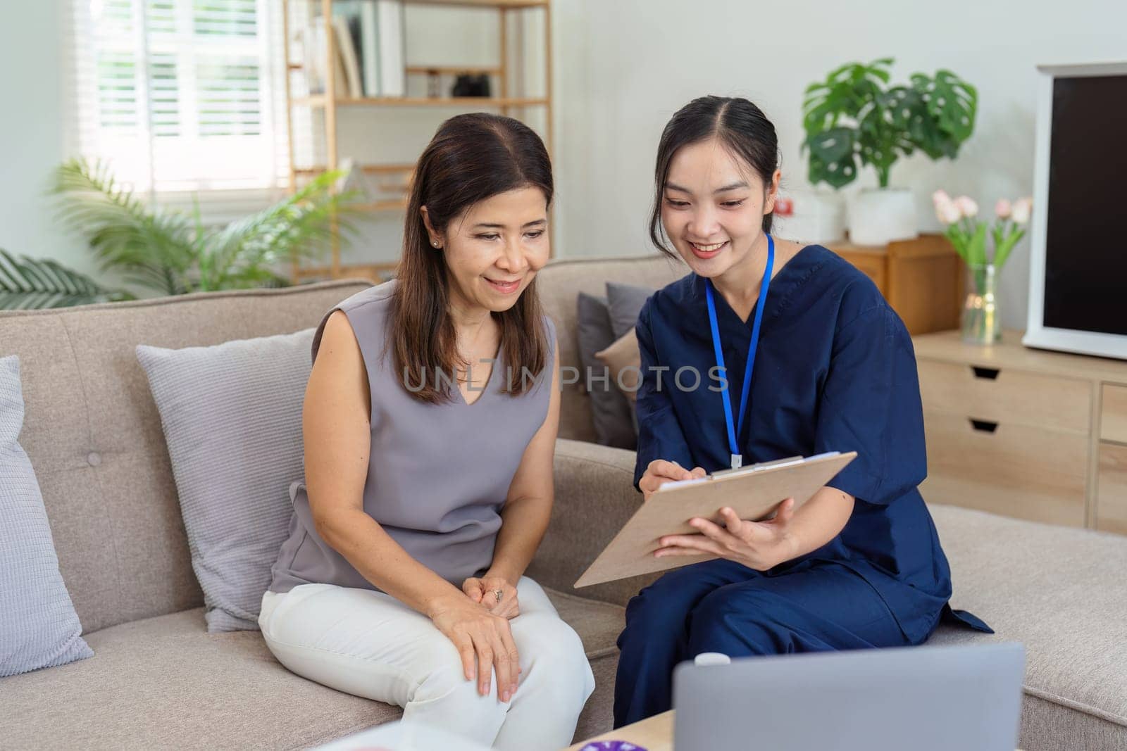 healthcare worker filling in a form with a senior woman during a home health visit by itchaznong