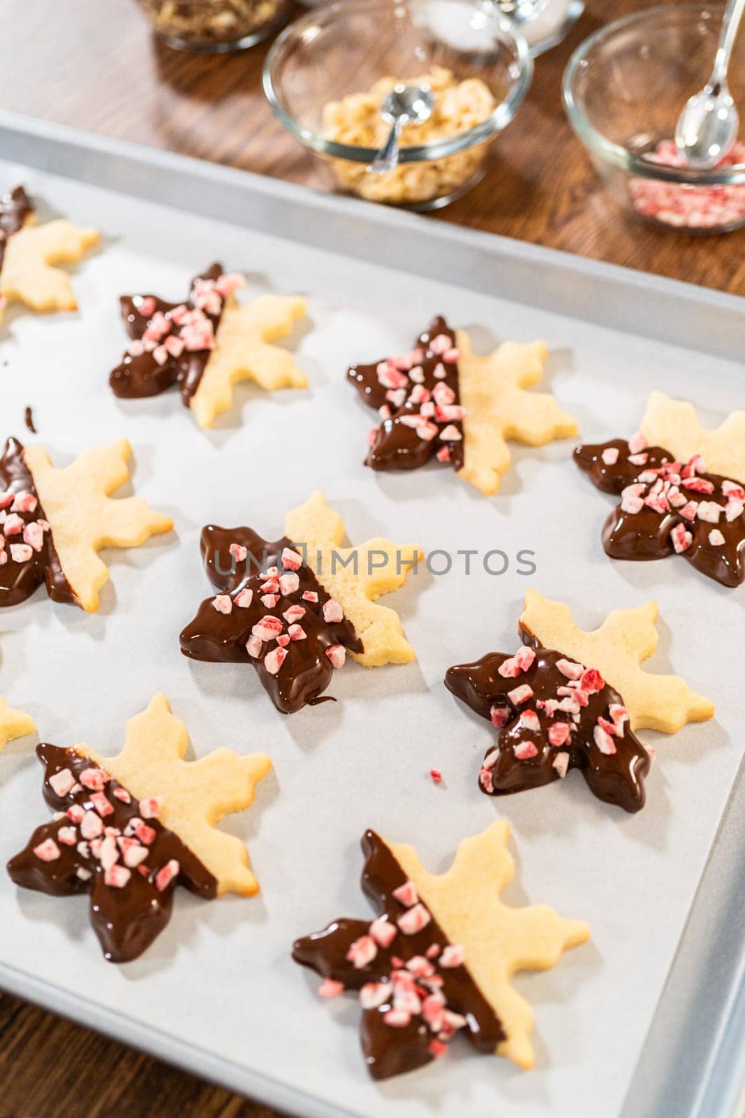 Preparing star-shaped cookies, half-dipped in chocolate, accented with peppermint chocolate chips for the holidays.