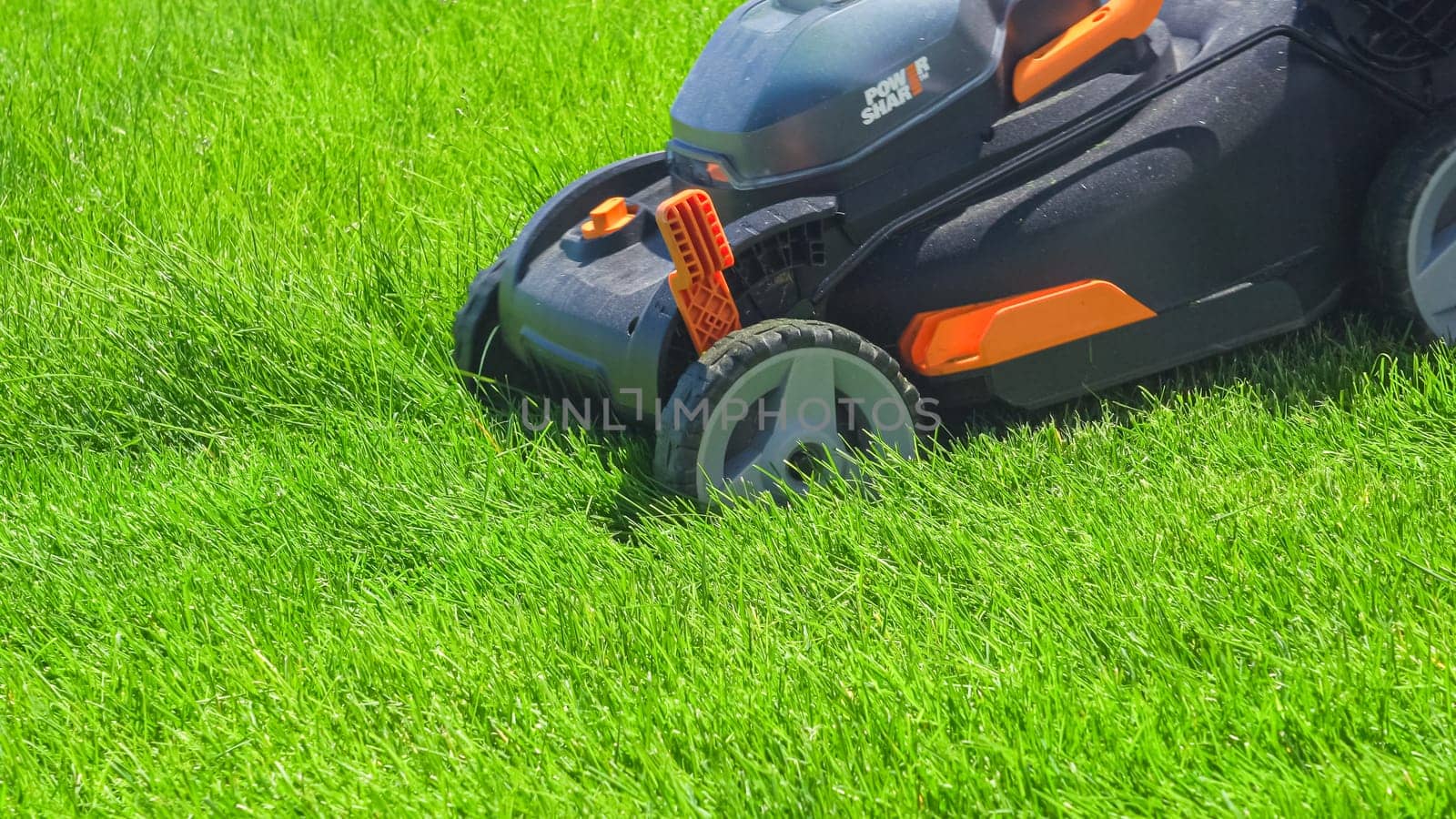 Castle Rock, Colorado, USA-June 25, 2023- At a residential suburban house, a lush green lawn is meticulously mowed using an electric lawn mower, creating a well-manicured and inviting outdoor space.