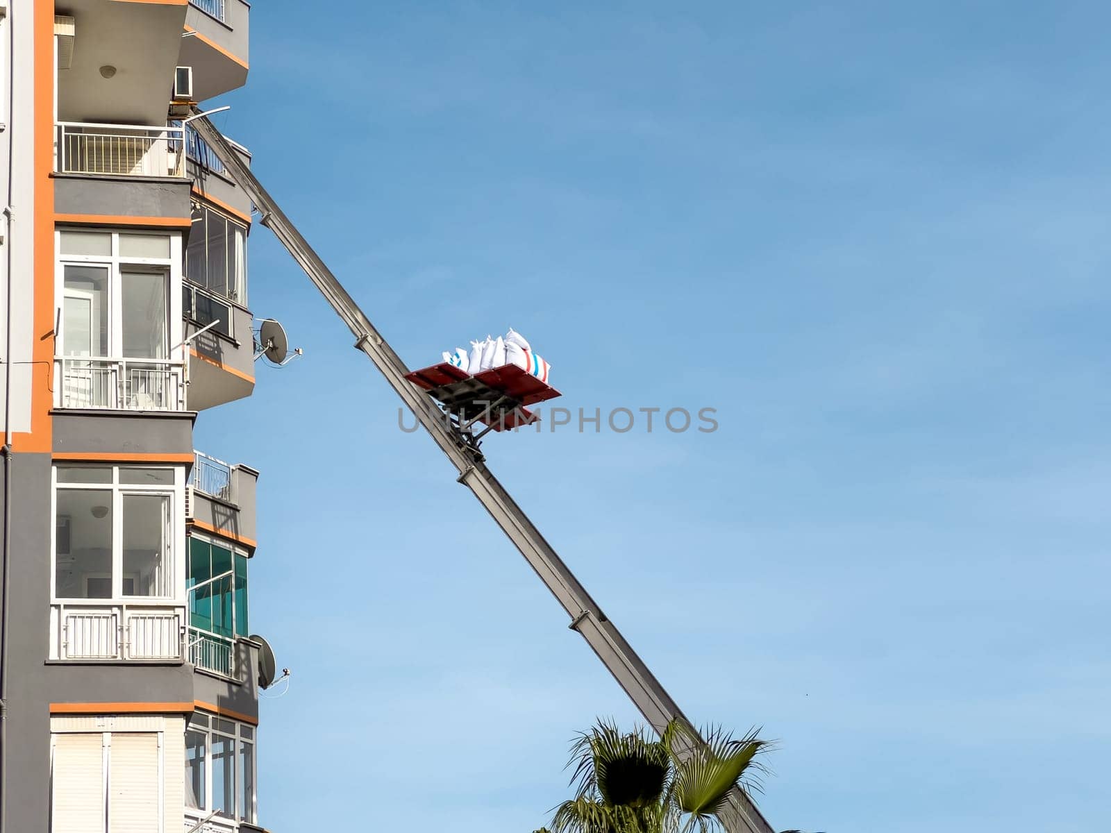 Home removal with hydraulic lift. Transporters carrying goods by elevator from the window of the building