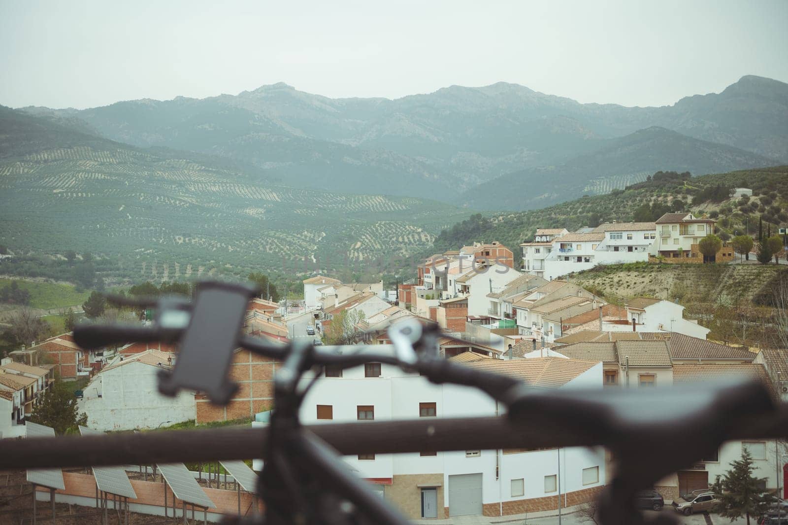 View through a blurred handlebar of an electric motor bike to a beautiful medieval city or village in mountains in Spain. E-bicycle - eco friendly mode of transportation. Bike sharing city service