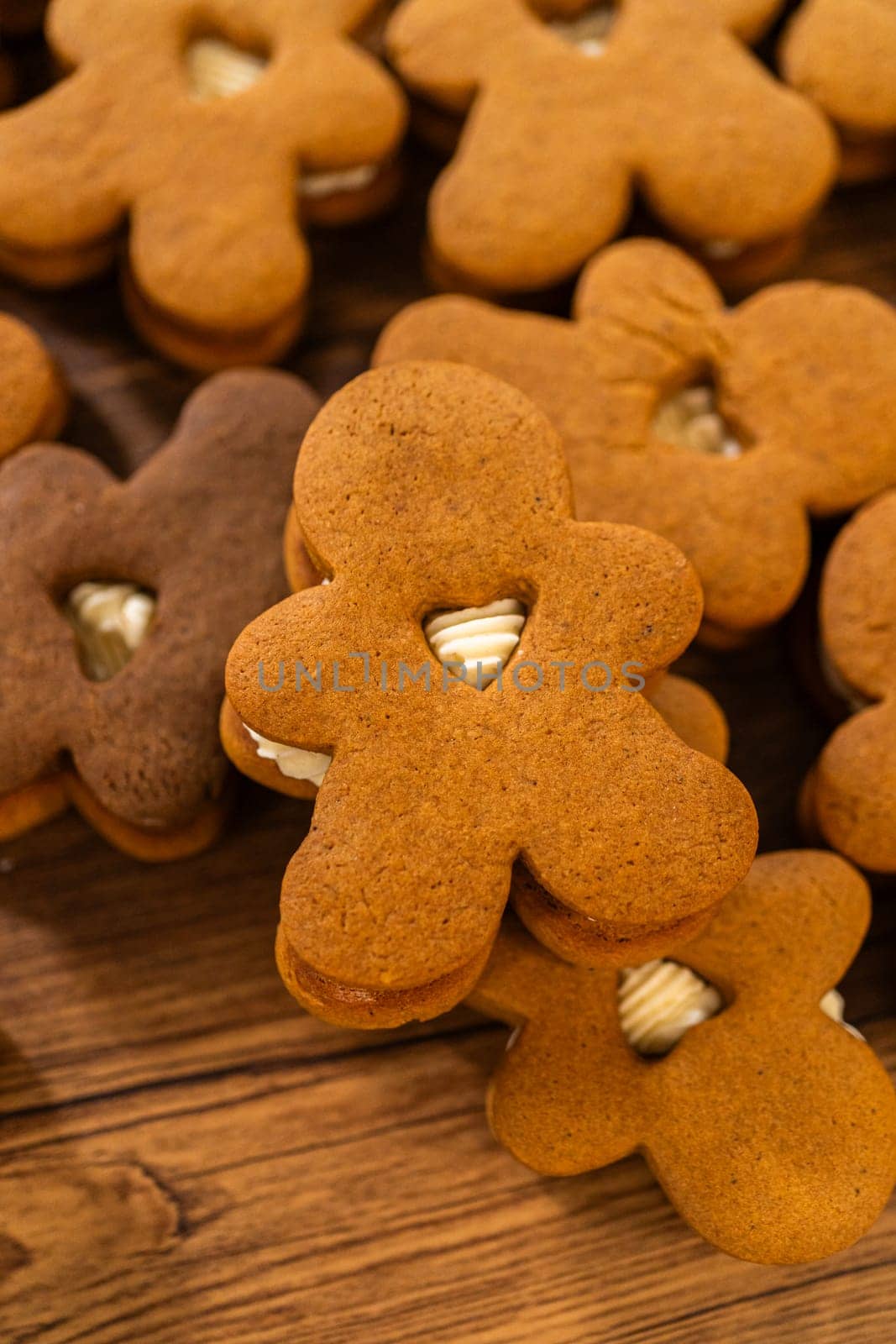 Making gingerbread man cookie sandwiches filled with eggnog buttercream, arrayed on a rustic wooden table, ideal for heartfelt Christmas gifting.